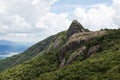 Horizontal view of a mountain rock face with some trees under a blue sky with white clouds - pico e serra do lopo