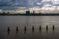 Horizontal view of New Jersey across the Hudson river with a stormy sky and pier pylons in the water