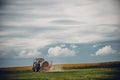 Horizontal view of a tractor in a green field under the blue sky Royalty Free Stock Photo