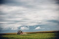 Horizontal view of a tractor on a green grass field under the blue cloudy  sky Royalty Free Stock Photo