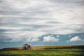 Horizontal view of a tractor on a green grass field under the blue cloudy  sky Royalty Free Stock Photo