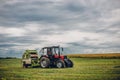 Horizontal view of a tractor on a green grass field under the blue cloudy  sky Royalty Free Stock Photo