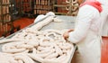 Horizontal view. A worker prepares sausages on a table at a meat processing factory, food industry Royalty Free Stock Photo