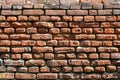 Horizontal wall texture of several rows of very old brickwork made of red brick. Shattered and damaged brick wall with pinched co Royalty Free Stock Photo