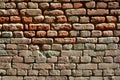 Horizontal wall texture of several rows of very old brickwork made of red brick. Shattered and damaged brick wall with pinched co Royalty Free Stock Photo