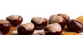 Horizontally many chestnuts with autumn leaves on white background Royalty Free Stock Photo