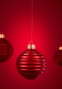 Horizontally ribbed Christmas balls hanging against burgundy red background
