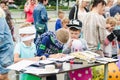 HORKI, BELARUS - JULY 25, 2018: Two small blindfolded boys draw on paper on a table and one little boy inflates a balloon on a sum Royalty Free Stock Photo