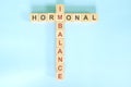 Hormonal imbalance concept. Wooden blocks crossword puzzle flat lay in blue background. Royalty Free Stock Photo