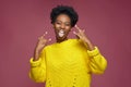 Horns rock and roll gesture. Happy cool audacious african american young woman sticking tongue, show rock-n-roll sign