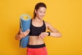 Horozontal shot of fitness woman after workout session checks results on smartwatch in fitness app, female with pefect body Royalty Free Stock Photo