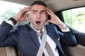 Horrified businessman stressed out in backseat