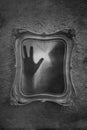 Horror concept of a ghostly figure trapped in a mirror. With a grunge, blurred, textured, black and white edit