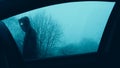 A horror concept. Looking up through a car window at a scary supernatural entity with glowing eyes, walking past a car. On a moody