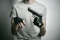 Horror and firearms topic: the killer with a gun in his hand in black gloves on a gray background in the studio Royalty Free Stock Photo