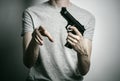 Horror and firearms topic: suicide with a gun on a gray background in the studio Royalty Free Stock Photo