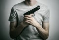 Horror and firearms topic: suicide with a gun on a gray background in the studio