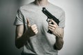 Horror and firearms topic: suicide with a gun on a gray background in the studio Royalty Free Stock Photo