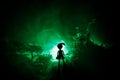 Horror Halloween decorated conceptual image. Alone girl with the light in the forest at night. Silhouette of girl standing between