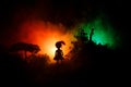 Horror Halloween decorated conceptual image. Alone girl with the light in the forest at night. Silhouette of girl standing between