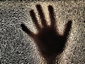 Horror hand. The shadow hand of human behind the glass. Corrugated textured glass through which children`s palm are visible