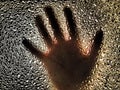 Horror hand. The shadow hand of human behind the glass. Corrugated textured glass through which children`s palm are visible Royalty Free Stock Photo