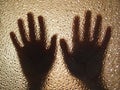 Horror hands. The shadow hands of human behind the glass. Corrugated textured glass through which children`s palms are visible Royalty Free Stock Photo