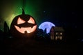 Horror view of Halloween pumpkin with scary smiling face. Head jack lantern with spooky building