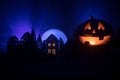 Horror view of Halloween pumpkin with scary smiling face. Head jack lantern with spooky building