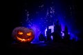 Horror view of Halloween pumpkin with scary smiling face. Head jack lantern with spooky building