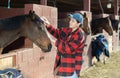 Horse care - female stable worker brushing horse