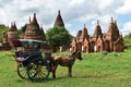 Horse drawn carriage tourists is driving along in front of the ancient temple of Bagan, Myanmar.