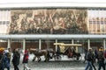 Horse Driven fiaker passing in street full of tourists in front of a DDR communist propaganda mural mosaic on Dresden Kulturpalast