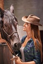 Horse, farm and smile with young woman in barn or stable for work in agriculture or sustainability. Cowgirl, texas or Royalty Free Stock Photo