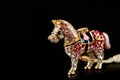 Horse figurine souvenir keychain in gold color ornate with bright pebbles shot on a dark background