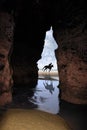 Horse galloping past cave Royalty Free Stock Photo