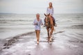 Horse riding by the sea. Woman on a brown horse. Man leading horse by its reins. Love to animals. Husband and wife spending time Royalty Free Stock Photo