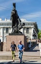 The Horse Tamer statue on Anichkov bridge and the a pair of tourists walking along Nevsky prospect.