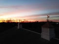 Horse weathervane on the cupola and the silhouette of trees against the orange-red sky at the sunset Royalty Free Stock Photo