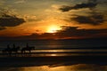 Horseback riders become a silhouette as the sun rises behind them over the ocean Royalty Free Stock Photo