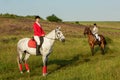 Horseback riders. Two attractive women ride horses on a green meadow