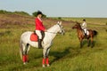 Horseback riders. Two attractive women ride horses on a green meadow