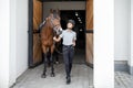 Horseman going with Thoroughbred horse near stable