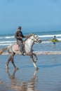 ESSAOUIRA/MOROCCO - MARCH 12, 2014: Horseman rides a gray horse along the ocean