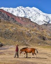 A Quechua man leads his horse along a mountain trail in the Peruvian Andes.