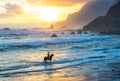 Horseriding at ocean beach on sunset background