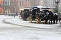 Horses carriage with old fashioned coach under snowfall on empty square in Europe. Winter travel background. Royalty Free Stock Photo