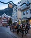 Horses pulling a carriage down a bustling street in Ortisei on Christmas in Alto Adige, Italy