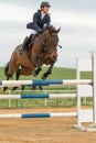 Horsewoman in high jump over a obstacle. Vertically.