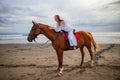 Horsewoman lays down on the withers of the horse. Caucasian woman in white dress riding horse on the beach. Copy space. Sunset Royalty Free Stock Photo